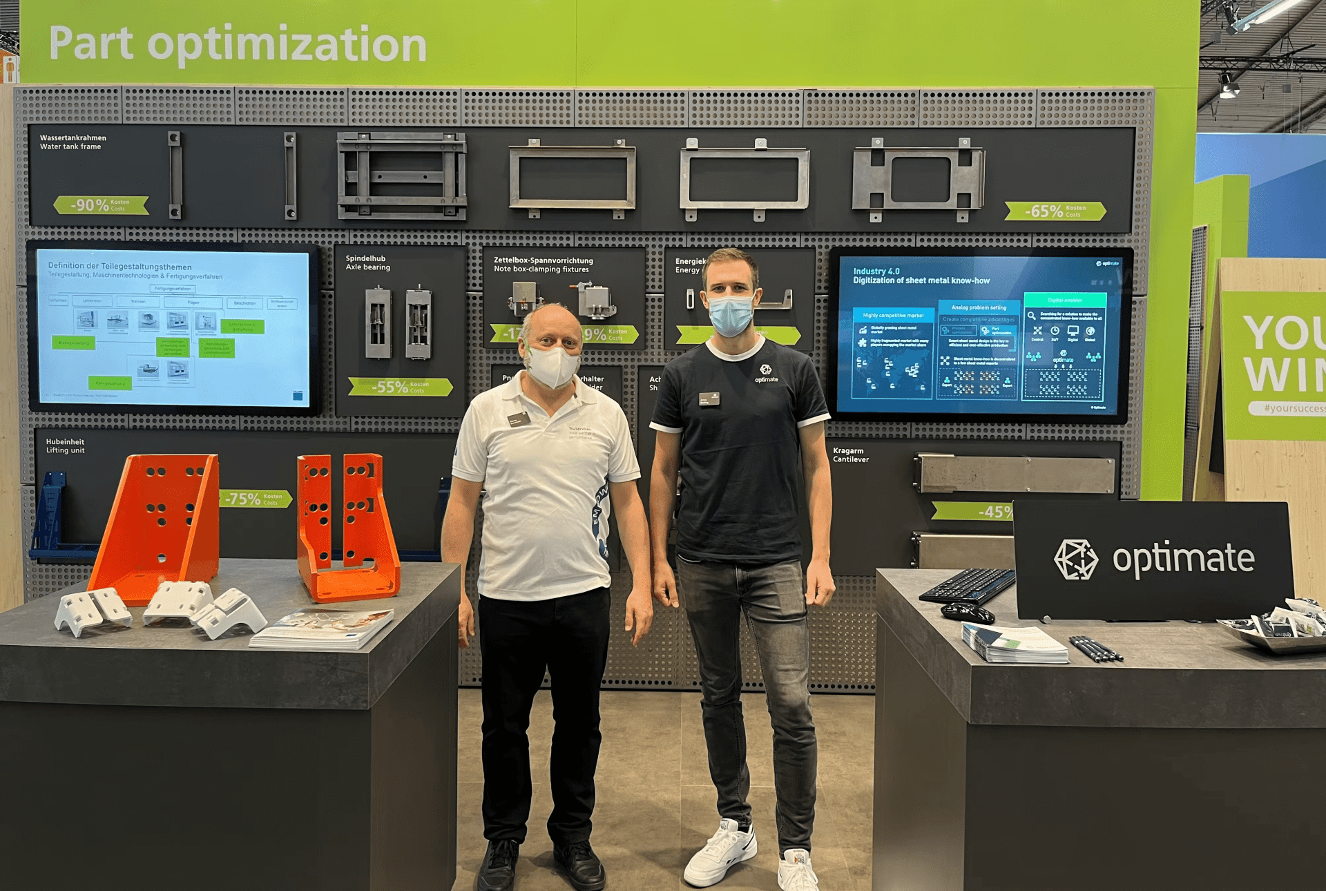 zwei personen stehen vor dem messestand von optimate